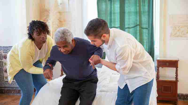 An elderly man receiving assistance from caregivers in a cozy home environment., tags: hüftfrakturen und - pexel